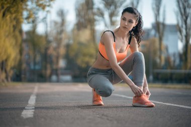 Güzel kıvırcık kadın gün batımında açık hava antrenmanından önce ısınıyor.