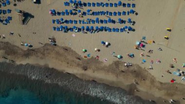 Gezginlerle dolu egzotik deniz kıyıları, gök mavisi suyu, şemsiye altında kalabalık, Tenerife, Kanarya Adaları