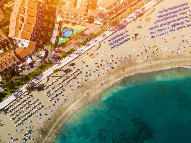 Turkuaz mavi şeffaf su, temiz kum ve tatil köylü oteli ile sahil kıyı şeridinin güzel hava dronu görüntüsü. Yüksek kaliteli resim