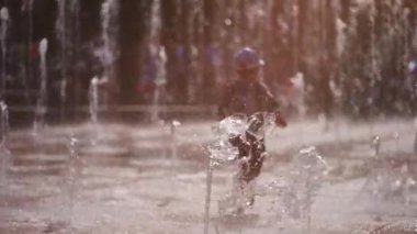 Neşeli çocuklar oynuyor, zıplıyor ve çeşme suyu püskürtüyor. Yüksek kaliteli FullHD görüntüler, yavaş çekim