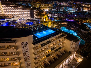 Tenerife, Kanarya Adası 'ndaki otelin çatısında mavi su aydınlatmalı modern yüzme havuzu. Yüksek kaliteli hava manzaralı fotoğraf