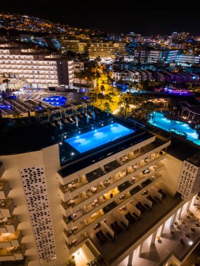 Tenerife, Kanarya Adası 'ndaki otelin çatısında mavi su aydınlatmalı modern yüzme havuzu. Yüksek kaliteli hava manzaralı fotoğraf