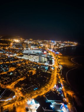 Okyanus kıyıları ve ışıkları, Tenerife, Kanarya Adası 'nın aydınlatılmış gece şehri ya da kasabasının güzel insansız hava aracı manzarası. Yüksek kalite fotoğraf