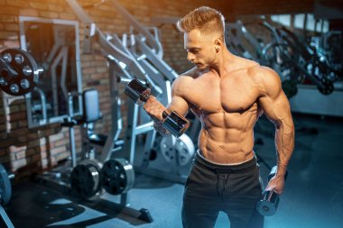 Vücutlu atletik kas geliştirici spor salonunda dambılla antrenman yapıyor, fitness sporcusu. Yüksek kalite fotoğraf