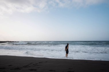 Sahilde yürüyen adam, bulutlu hava, güzel okyanus dalgaları. Yüksek kalite fotoğraf