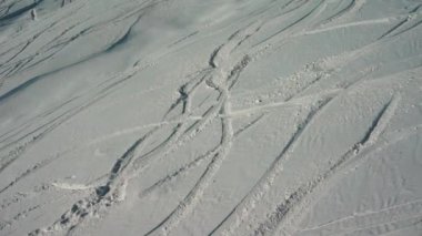 Kayakçılardan ve snowboardculardan sonra karlı tepede taze izler.