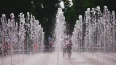 Neşeli çocuklar oynuyor, zıplıyor ve çeşme suyu püskürtüyor. Yüksek kaliteli FullHD görüntüler, yavaş çekim