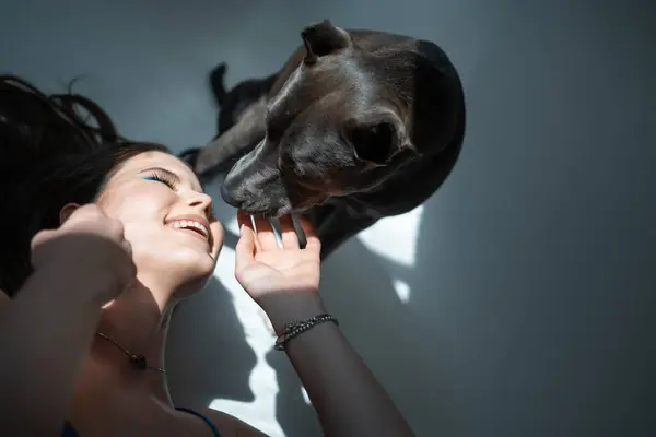 pretty young woman playing with pet at house