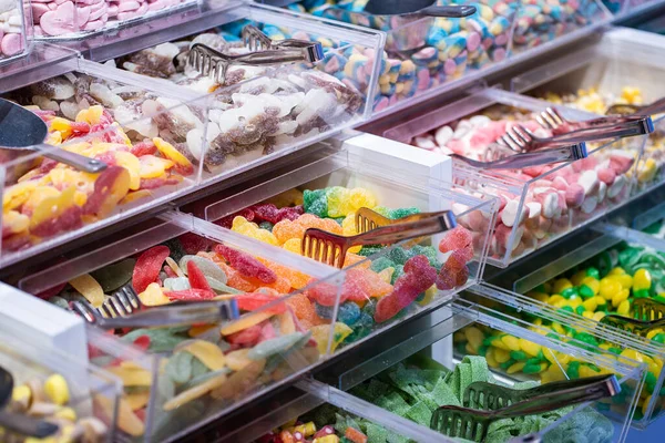 showcase of candy shop, transparent container with various sweets, marshmallow, jelly, chewy gums, rich sugar assortment. High quality photo