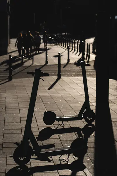 electric scooter rental at city street, parked eco vehicle outdoor, shadow and silhouette. High quality photo