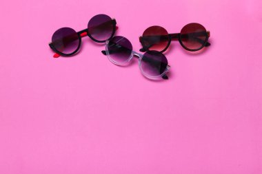 Pembe ve mor arka planda uzanan lüks ve modaya uygun güneş gözlükleri, düz bir manzara. Yüksek kalite fotoğraf