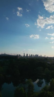 Günbatımında Varşova şehrinin gökdeleni ve PGE Narodowy Stadyumu şehir merkezinin ve yeşil parkın gökdelenleri, gökyüzü manzarası. Yüksek kalite 4k görüntü, dikey video