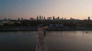 Günbatımında Vistula nehri üzerinde yeni inşa edilmiş yaya ve bisiklet modern köprüsü, şehir merkezindeki finans bölgesi ve Varşova şehrinin modern mimarisi, gökyüzü manzarası 4k. Yüksek kaliteli görüntüler