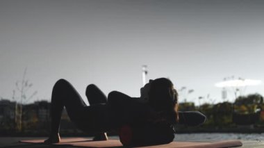 Aktif fitness kadını masaj köpüğü rulo ile kas gevşeme egzersizi yapıyor. Spor antrenmanı, sırt ağrısı ve vücut ağrısından sonra fasiyal tahliye teçhizatıyla esniyor. Yüksek kaliteli görüntüler