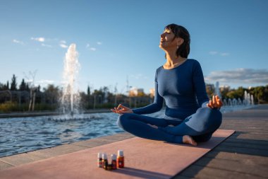 Genç bir kadın aroma yağı ve aromalı terapi şişeleriyle meditasyon yapıyor. Kokulu terapi konsepti. Yüksek kalite fotoğraf