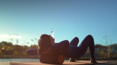 Aktif fitness kadını masaj köpüğü rulo ile kas gevşeme egzersizi yapıyor. Spor antrenmanı, sırt ağrısı ve vücut ağrısından sonra fasiyal tahliye teçhizatıyla esniyor. Yüksek kaliteli görüntüler
