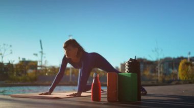 Gün batımında yoga yapan genç, güzel bir kadın. Vücut bilinci açık olan, köpük silindirli, bloklu, kokulu Hint sopalı ve diğer aksesuarlarla egzersiz yapan biri. Yüksek kalite 4k görüntü