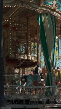 Mutlu çocuklarla dolu renkli bir atlıkarınca lunaparktaki antika kavşağında neşeli çocuklar, dikey video görüntüleri. Yüksek kalite 4k görüntü