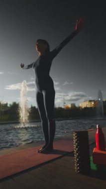 Gün batımında yoga yapan genç, güzel bir kadın. Vücut bilinci açık olan, köpük silindirli, bloklu, kokulu Hint sopalı ve diğer aksesuarlarla egzersiz yapan biri. Yüksek kalite 4k görüntü