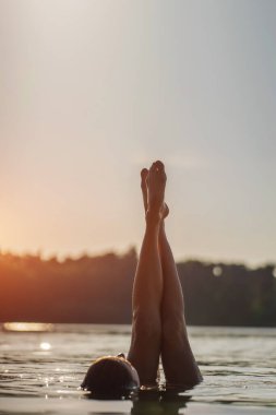 Mutlu, huzurlu bir kadın yaz tatili yapar ve plajda dinlenir, mavi suyla bacaklar oynar ve su sıçratır, eğlenir ve güneşin tadını çıkarır. Yüksek kalite fotoğraf