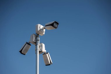 Güvenlik kameraları açık mavi gökyüzü çevresindeki kutuplara monte edilmiş, şehir konseptinde güvenlik kameraları var. Yüksek kalite fotoğraf