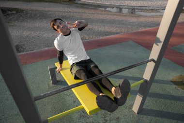 Genç atletik adam gün batımında spor salonunda vücut geliştirme ve dayanıklılık antrenmanı konseptinden sonra gevşemek için spor salonunda kas egzersizi yaptıktan sonra dinleniyor. Yüksek kalite fotoğraf