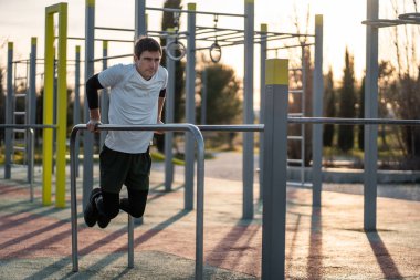 Genç atletik adam vücut geliştirme ve dayanıklılık eğitimi için gün batımında spor salonunda dalgıçlık yapıyor. Yüksek kalite fotoğraf