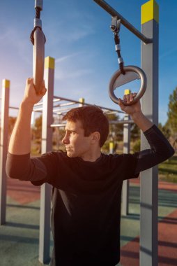 Gün batımında spor salonunda spor yaptıktan sonra dinlenen genç atletik adam vücut geliştirme ve dayanıklılık eğitimi sırasında ara veriyor. Yüksek kalite fotoğraf