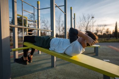 Gün batımında spor salonunda spor salonunda antrenman yapan, vücut geliştirme ve dayanıklılık eğitimi alan genç bir sporcu. Yüksek kalite fotoğraf