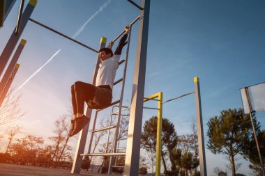 Genç atletik adam spor yapıyor spor yapıyor ve gün batımında karın kasları için sallanan bacakları kaldırıyor. Spor salonunda karın kasları, vücut geliştirme ve dayanıklılık eğitimi. Yüksek kalite fotoğraf