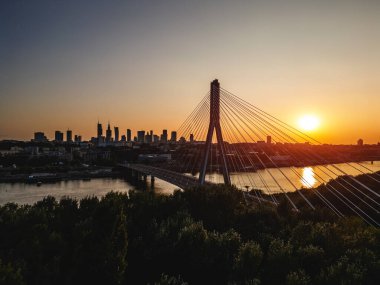 Günbatımında Vistula nehri üzerinde modern kablo köprüsü olan Varşova şehrinin ufuk çizgisi, arka planda modern gökdelenler, hava manzarası. Yüksek kalite fotoğraf