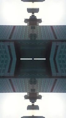 Modern uzun gökdelen binasının ve şehir ortamının ayna fraktal etkisi simetri camı ve metal dış görünüş, teknolojik soyut arka plan, büyüleyici. Yüksek kaliteli görüntüler, 4k dikey video