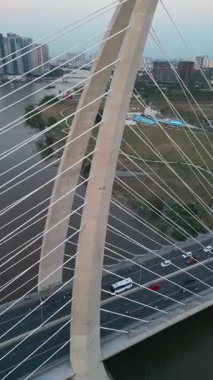 Saigon nehri üzerinde aydınlatma ışıkları olan modern kablolu köprü, arka planda finans merkezi, Ho Chi Minh şehri, Vietnam hava manzaralı. Yüksek kalite 4k görüntü, dikey video