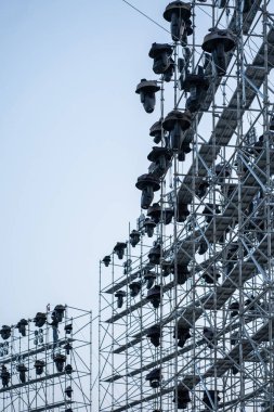 İnşaat işçileri, açık hava konseri, profesyonel sahne aydınlatma ekipmanı inşaatı için büyük iskeleler ve metal platformlar kuruyorlar. Yüksek kalite fotoğraf