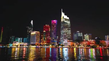 Aydınlatılmış Ho Chi Minh şehir silueti ve Saigon nehri gece görüşü, yüksek gökdelen kuleleri, Vietnam hava aracı manzaralı finans merkezinin neon sokak ışıkları. Yüksek kalite 4k video