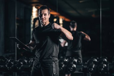 Spor salonuna hazırlanan tabletli kendinden emin erkek antrenör elinde tabletle antrenman için hazır bekleyen erkek fitness koçu. Yüksek kalite fotoğraf
