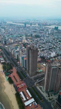 Da Nang şehrinin canlı sahili ve şehir siluetini gösteren hava görüntüsü, canlı kıyı şeridini ve modern şehir manzarasını gözler önüne seren insansız hava aracı. Yüksek kalite 4k görüntü, dikey video