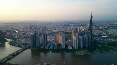 Ho Chi Minh şehir silueti ve Saigon nehri üzerinde güzel bir gün batımı yeşil tropikal park ve yüksek gökdelen kuleleri, Vietnam hava aracı manzaralı şehir merkezi bölgesi. Yüksek kalite 4k video