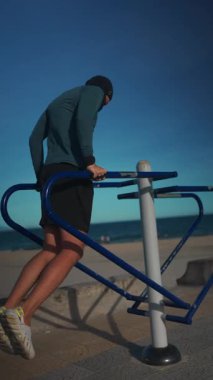 Erkek vücut geliştirici gün batımında paralel barlarda dalış yapıyor, Sporcu adam gün batımında açık hava ekipmanlarıyla trisepsleri eğitiyor. Yüksek kalite 4k görüntü