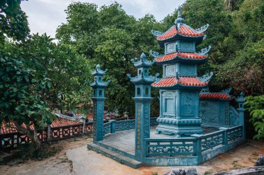 Süslü mavi yapısı ve orman ortamında kırmızı kiremitli çatısı olan geleneksel Vietnam tapınağı, verimli yeşilliklerle çevrili karmaşık mimari detayları olan barışçıl Budist tapınağı. Yüksek kalite fotoğraf