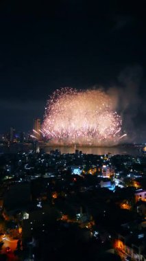 Han nehri üzerindeki Vietnam havai fişek festivali sırasında şehrin ufuk çizgisinde yaşanan renkli patlama şenlik gecesi kutlamalarında Da Nang 'ın havadan görüntüsünü aydınlattı. Yüksek kalite 4k görüntü, dikey video