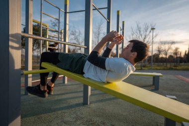Gün batımında spor salonunda spor salonunda antrenman yapan, vücut geliştirme ve dayanıklılık eğitimi alan genç bir sporcu. Yüksek kalite fotoğraf