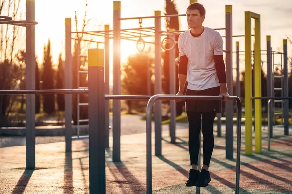 Genç atletik adam vücut geliştirme ve dayanıklılık eğitimi için gün batımında spor salonunda dalgıçlık yapıyor. Yüksek kalite fotoğraf