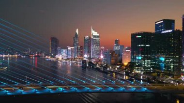 Saigon nehri üzerinde aydınlatma ışıkları olan modern kablolu asma köprü, arka planda finans merkezi, Ho Chi Minh şehri, Vietnam hava aracı manzaralı. Yüksek kalite 4k görüntü