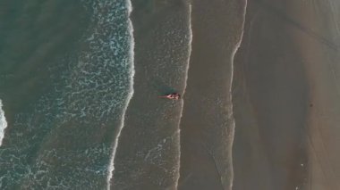 Deniz dalgaları, yaz tatili ve doğa güzelliğiyle kumsalda uzanan bikinili bir kadının havadan görünüşü kıyı şeridi boyunca kadın yolcuların en iyi bakış açısı. Yüksek kalite 4k görüntü