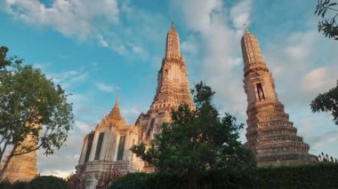 Gün batımında Bangkok 'taki Wat Arun tapınağı, Chao Phraya' daki ikonik Tayland pagoda altın kuleleri, tarihi mimari ve kültürel ışıltı. Yüksek kalite 4k video