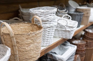 Close-up selective focus of various wicker flower pots and baskets on a shelf in a gardening store.