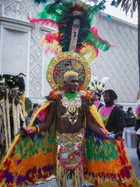 Menton, France-February 18, 2019: Unidentified african american man dressed colorful carnival costume with color feathers marching during the traditional carnival parade of the Menton Lemon Festival.