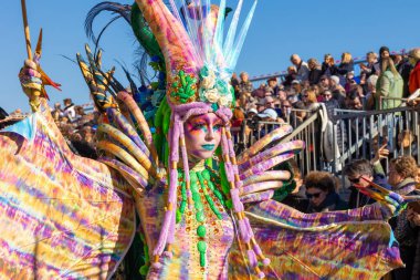 Menton, France-February 12, 2023: Close up woman dressed colorful fantastic carnival costume marching during the traditional carnival parade of Lemon Festival.