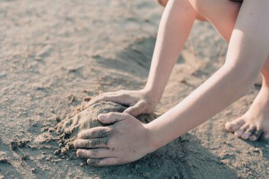 Yazın kumsalda kumla oynayan çocukların elleri. Tatil kavramı
